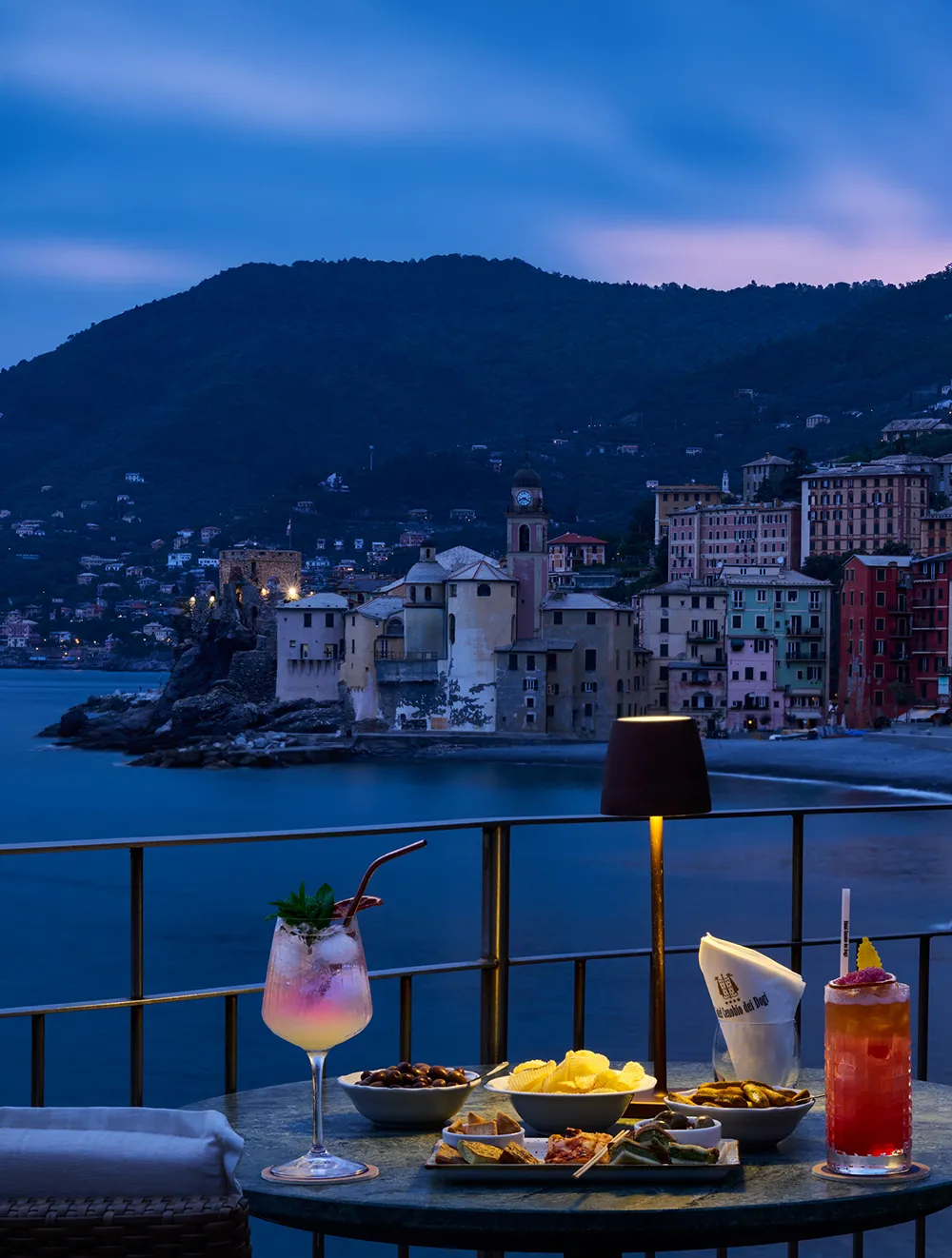 Aperitif auf der Terrasse bei Sonnenuntergang mit Blick auf das beleuchtete Camogli