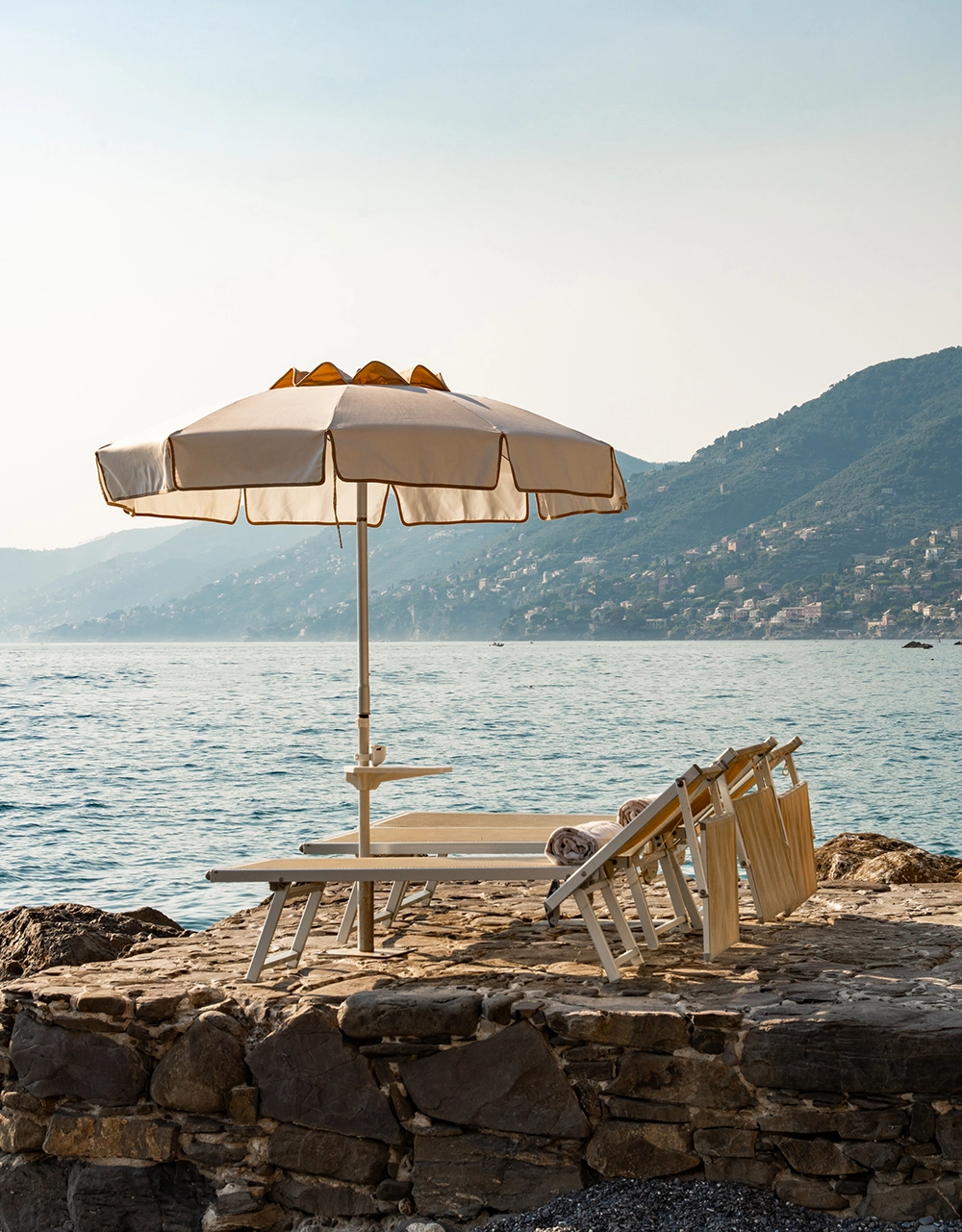 Sonnenschirm und Liegen auf den Felsen am Golfo Paradiso