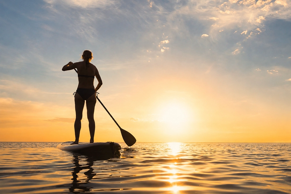 Stand-up-Paddling bei Sonnenuntergang auf dem Meer