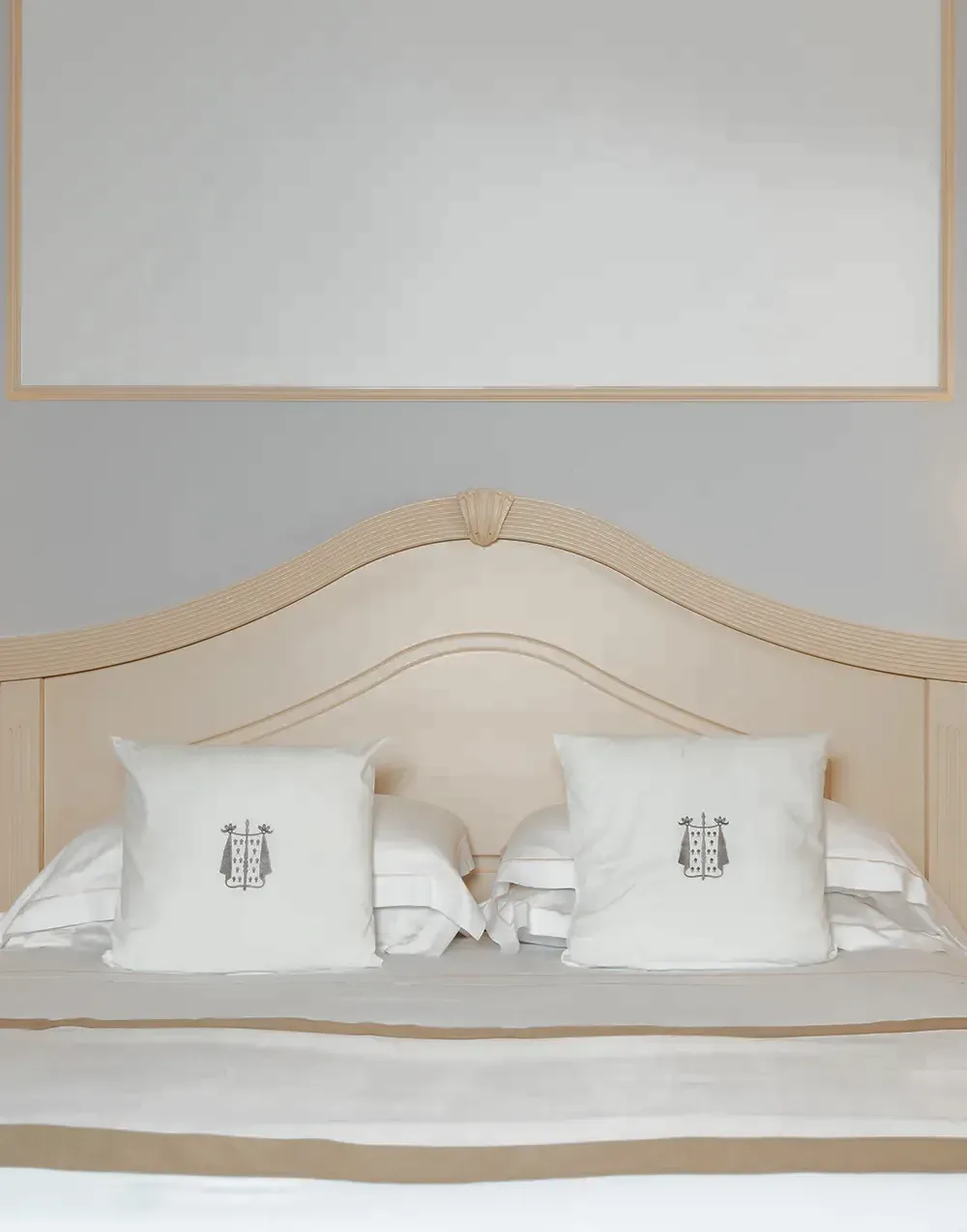 Bett der Suite mit Kissen, bestickt mit dem Hotelwappen